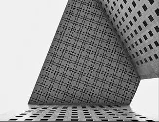 Angle d’un immeuble de bureaux vu en contre-plongée, façade en damier