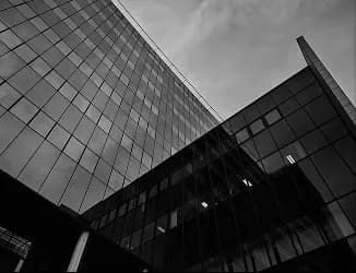 Façade vitrée courbe reflétant le ciel, en noir et blanc
