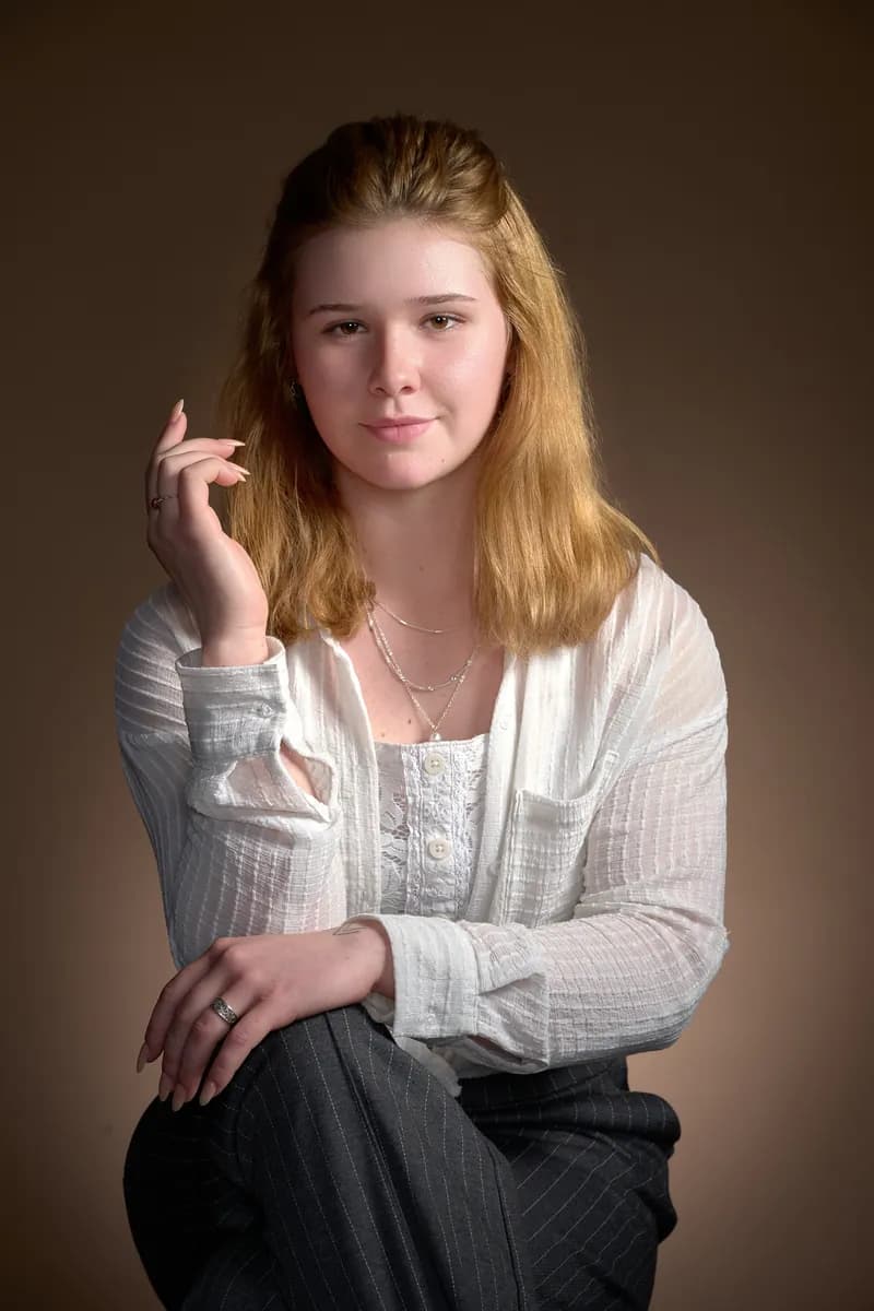 Portrait d’une jeune femme blonde en chemise blanche sur fond brun
