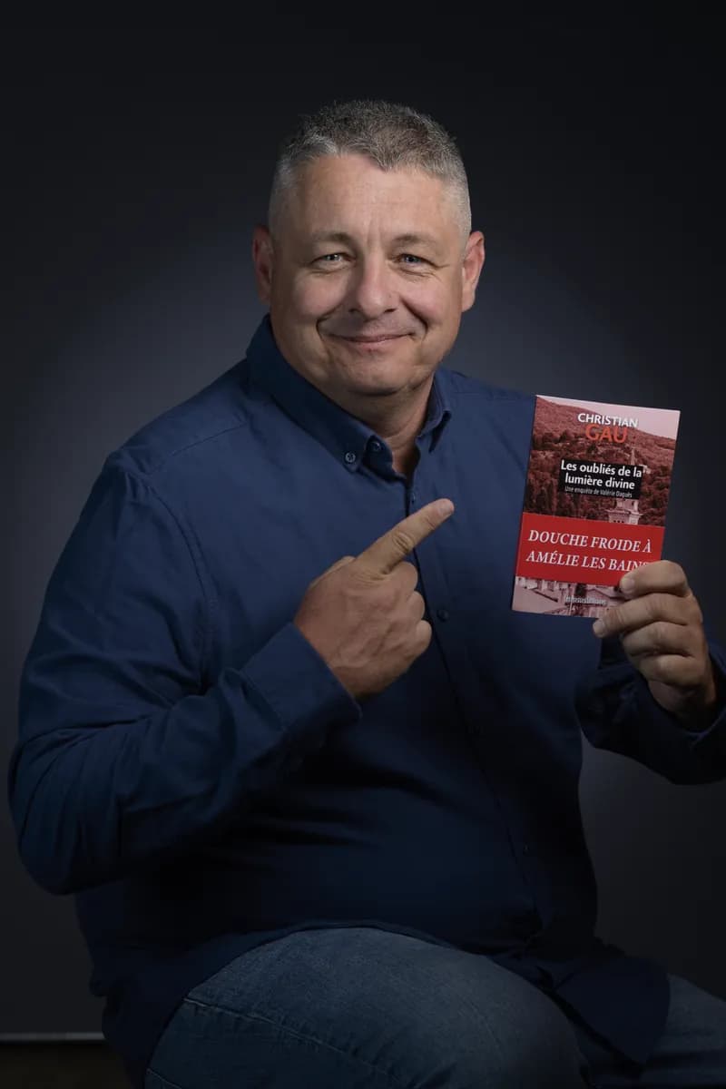 Portrait d’un auteur en chemise bleue présentant son livre
