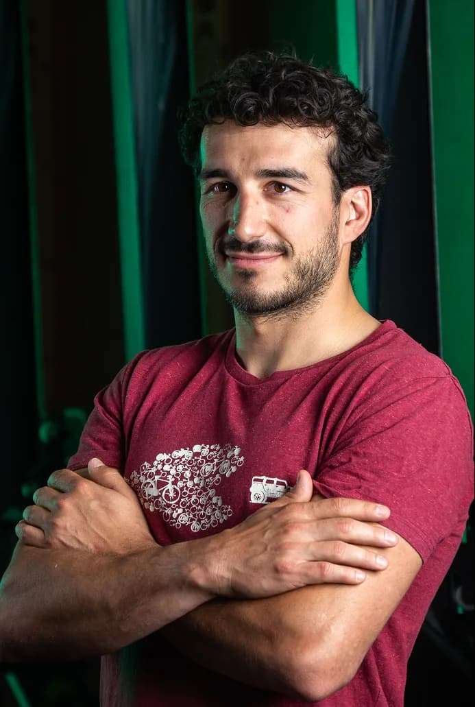 Portrait d’un sportif en t-shirt bordeaux, bras croisés, sur fond vert
