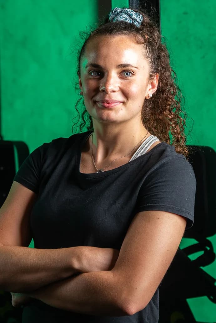 Portrait d’une sportive aux cheveux bouclés, bras croisés, sur fond vert